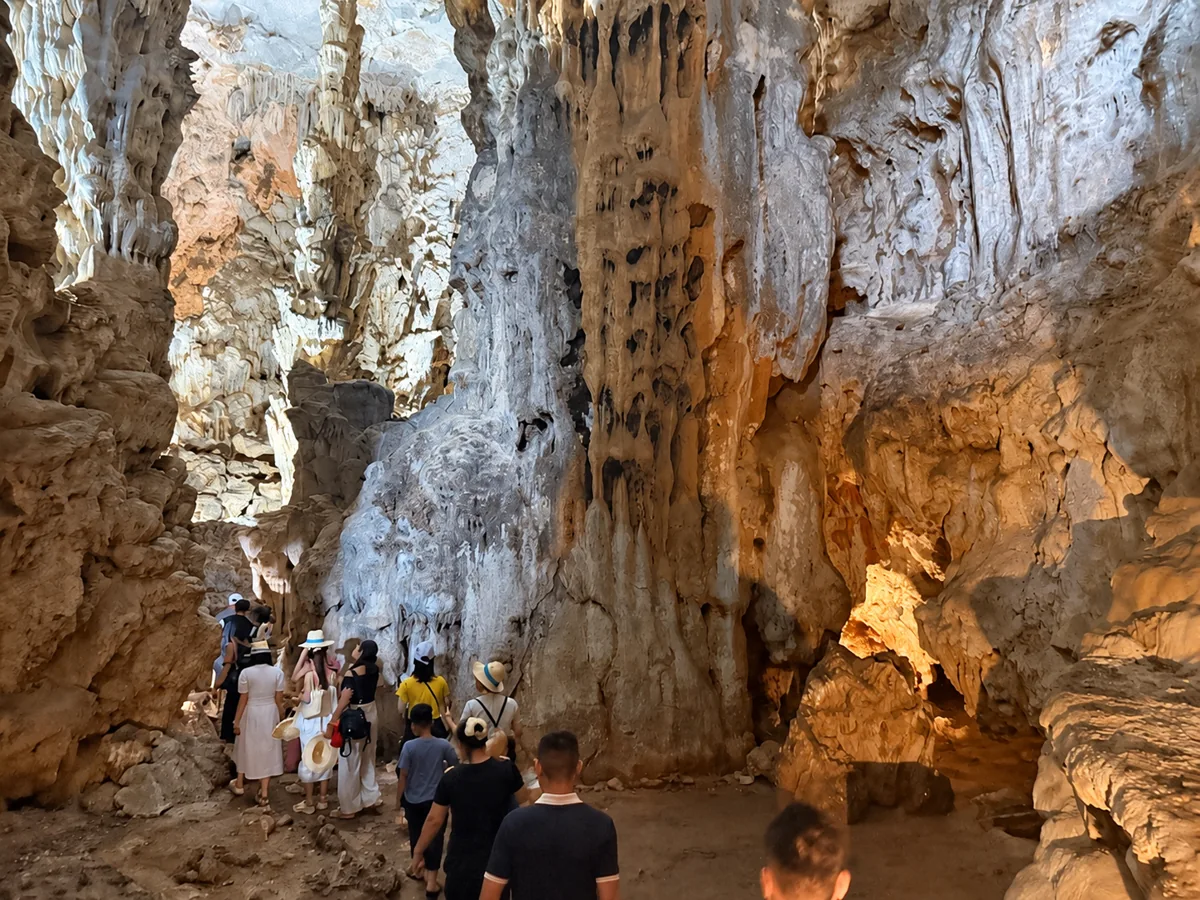 Du khách trên lối tham quan giữa các khối đá trong hang Đầu Gỗ, ảnh tư liệu chỉnh độ rõ bằng AI