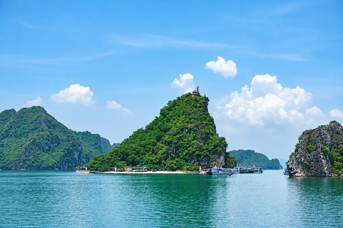 Đảo Ti Tốp với sườn núi xanh và bãi biển dưới chân đảo; ảnh tư liệu được tăng nét bằng AI